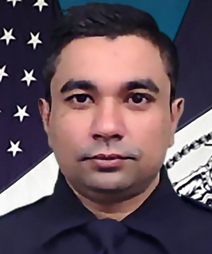 Police officer in uniform in front of the American flag, formal portrait.