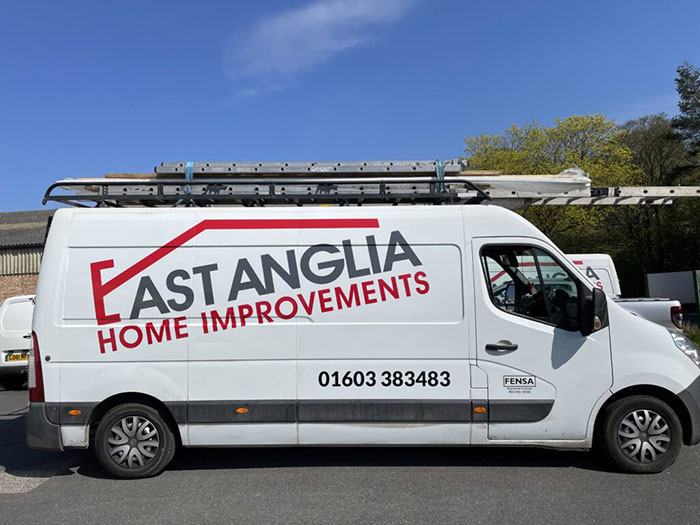 White van with East Anglia Home Improvements logo parked outside under clear blue sky