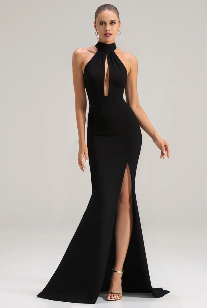 Woman in elegant black halter gown with keyhole neckline and high slit, posing confidently in studio setting.