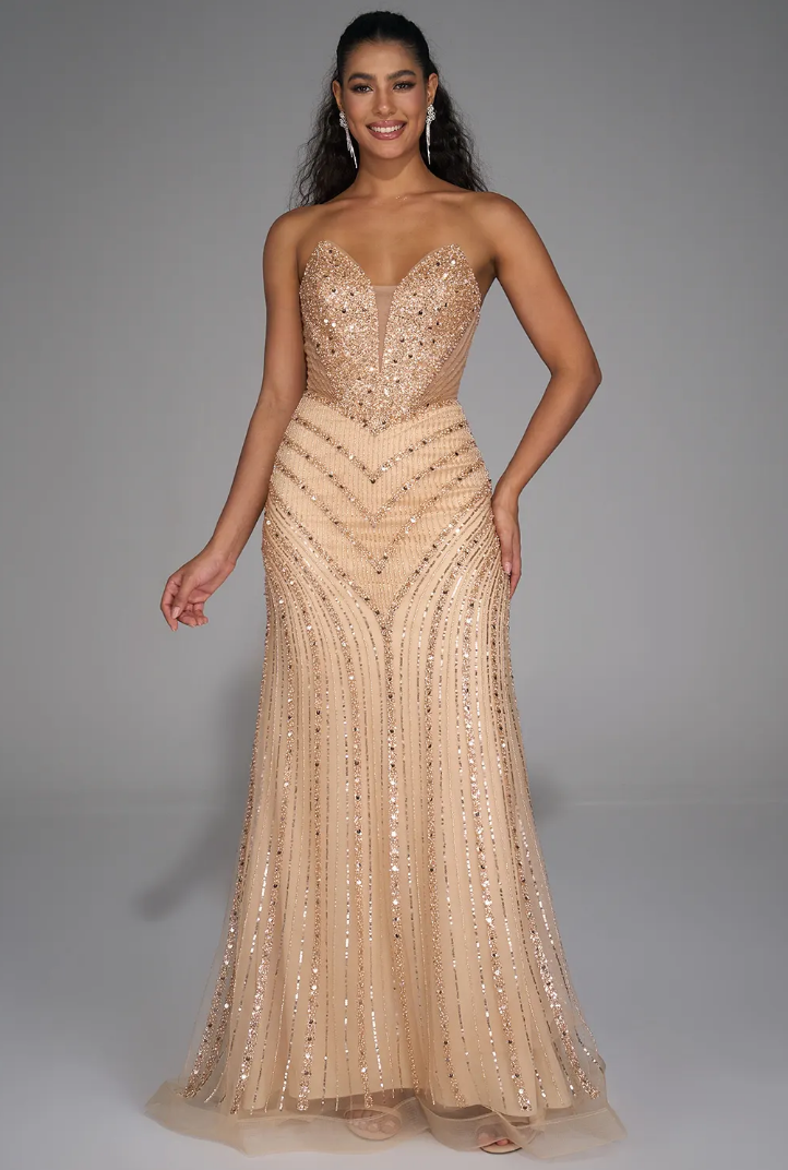 Woman in a sparkling, nude-colored gown posing confidently against a neutral background.