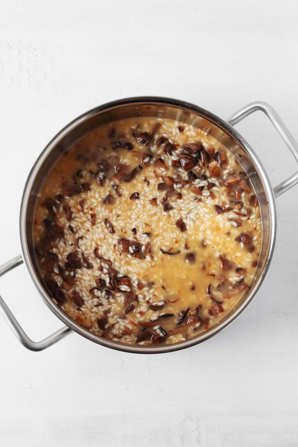 An overhead image of a silver pot, which is filled with a vegan mushroom risotto.